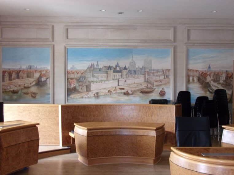 Salle d’audience avec estrades en bois, sièges et grande fresque murale, vue côté magistrats
