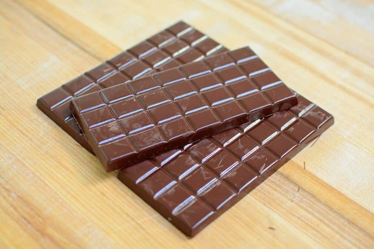 Tablettes de chocolat alignées sur un plan de travail, éclairage doux, texture visible et nette