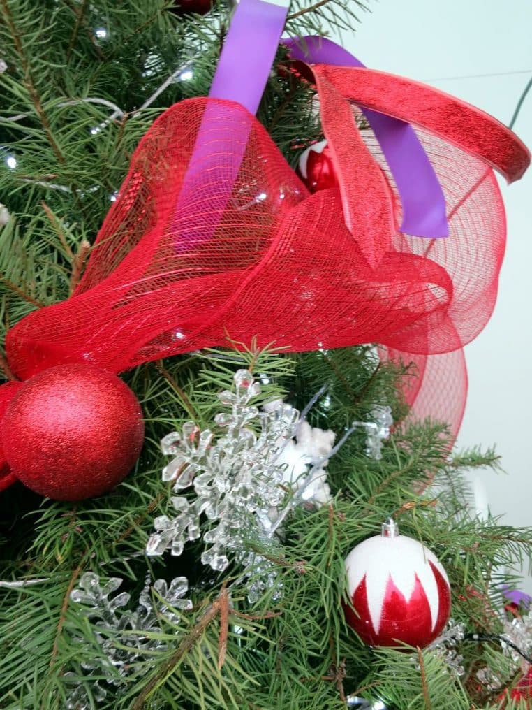 Ensemble de décorations de sapin de Noël colorées suspendues sur des branches, avec un fond doux et légèrement flouté.