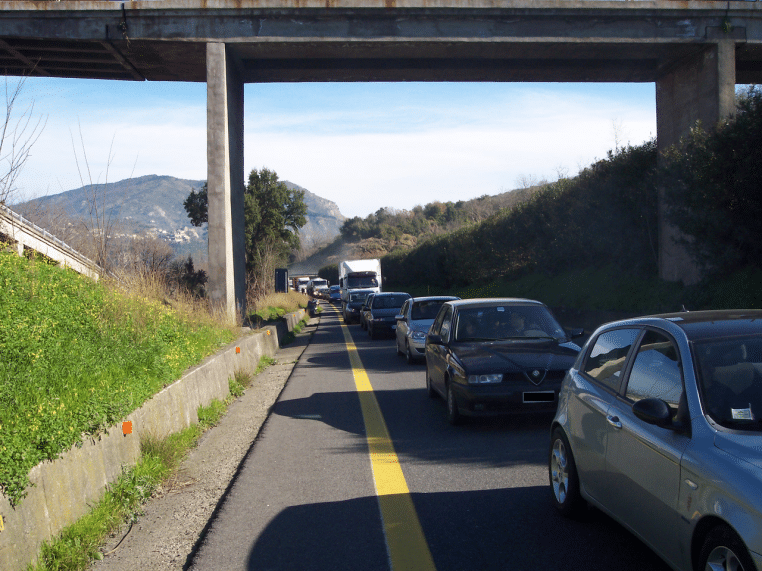 Embouteillage sur l’autoroute A3 en Italie, véhicules à l’arrêt sous un pont, avec longue file sur une voie.