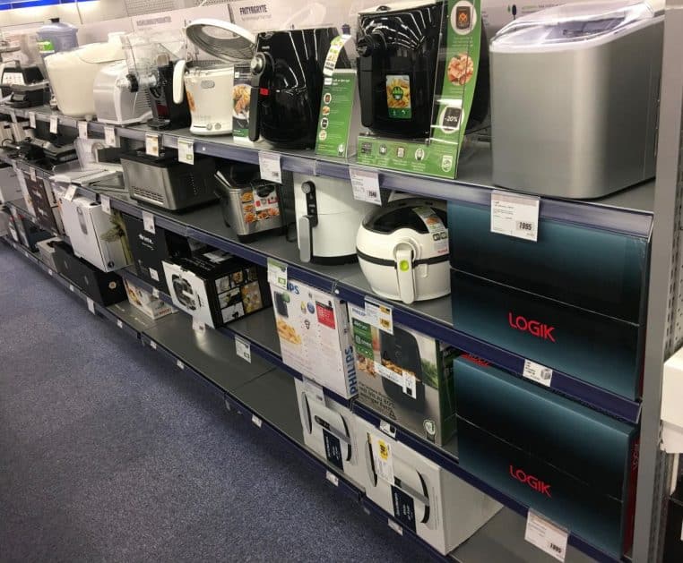 « Allée d’électroménager en magasin, petits appareils alignés et boîtes en bas de rayonnage, perspective en largeur »