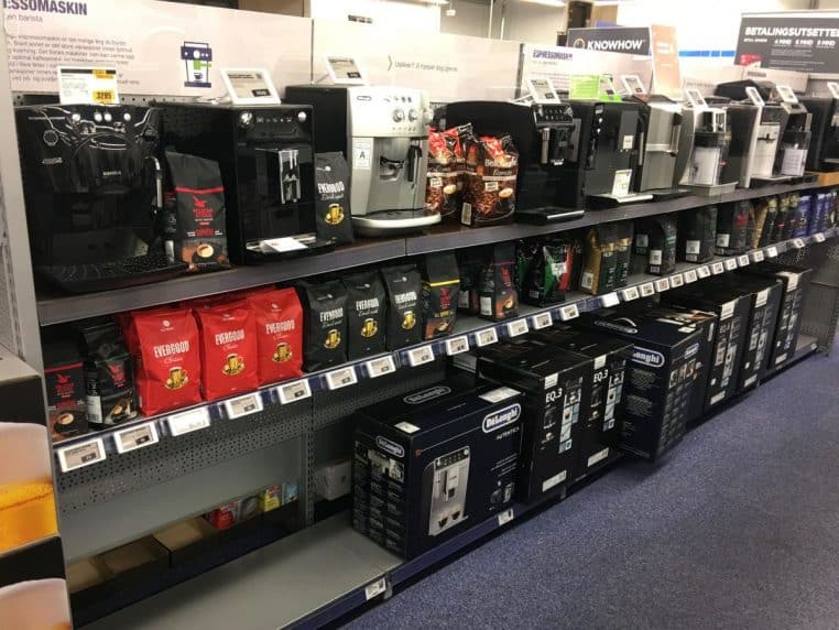 Rayon d’un magasin d’électronique avec machines à café, étiquettes prix et cartons en réserve, vue en biais » Crédit : Wolfmann / Wikimedia Commons.