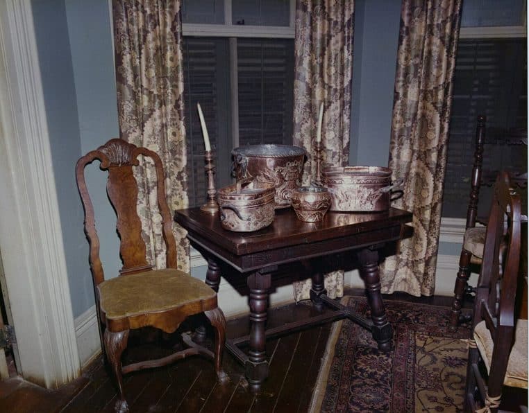 Intérieur de maison ancien avec table et chaises près d’une fenêtre, ambiance calme d’un foyer à préserver