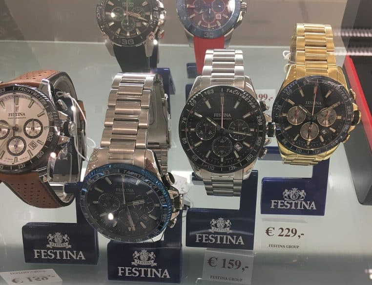 Vitrine de montres chronographes en boutique, plusieurs modèles alignés, cadrans et bracelets bien visibles.