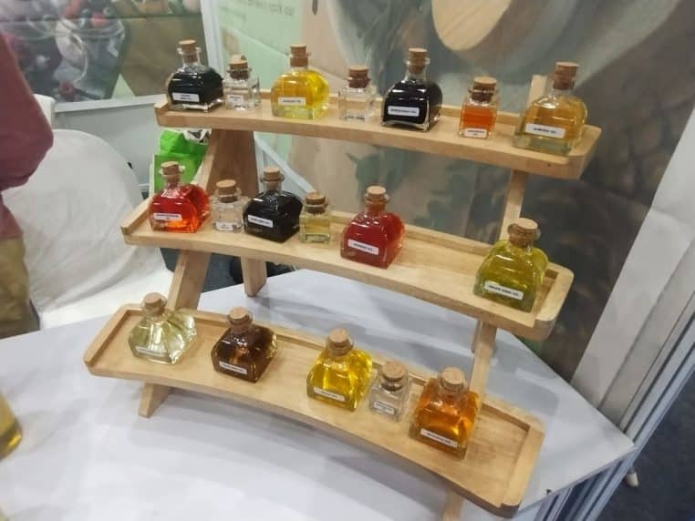 Présentoir de petits flacons d’huiles aux teintes ambrées et dorées, photographié en format paysage