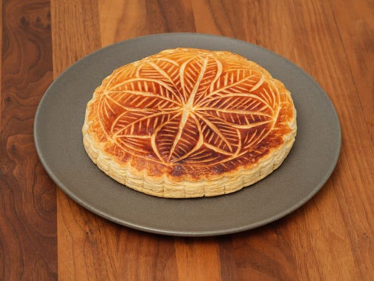Galette des rois dorée sur table, pâte feuilletée bien levée et brillante, vue de dessus, ambiance maison.