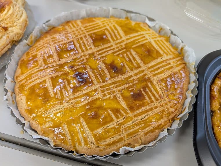 Galette des rois entière, feuilletage marqué, servie en intérieur, lumière douce, prise de vue gourmande.