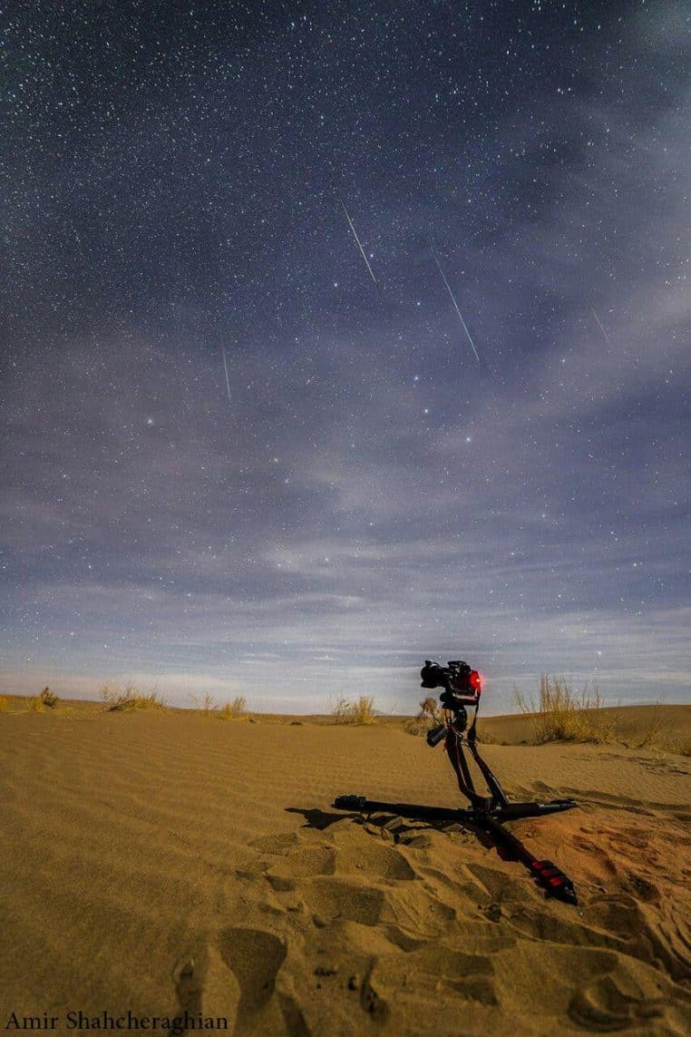 Ciel nocturne de désert où plusieurs météores des Géminides traversent la voûte étoilée au-dessus d’un horizon sombre, capturés en longue pose.