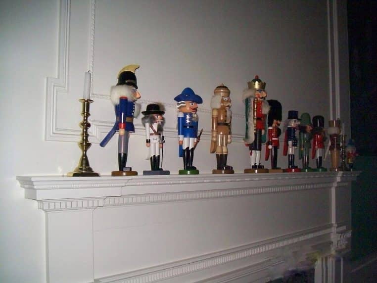 Collection de casse-noisettes en bois exposés sur une table de fête, décorations de Noël et éclairage intérieur.