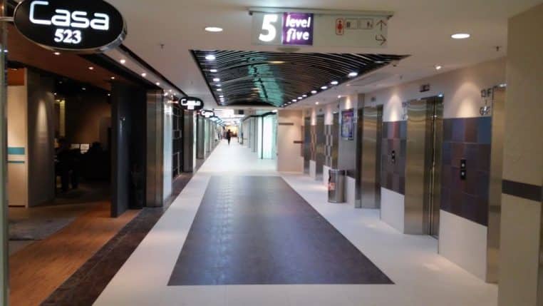 Couloir de centre commercial avec enseignes lumineuses et ascenseurs, perspective centrale, ambiance intérieure nette et éclairée