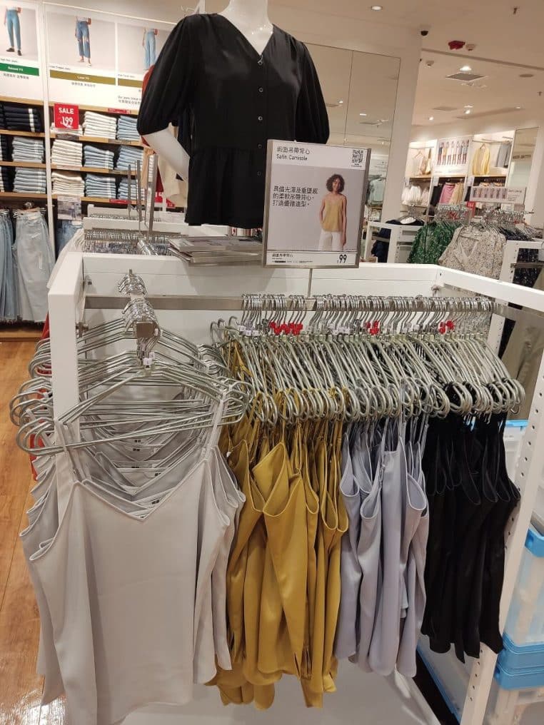 Vue d’une boutique Uniqlo avec portants de vêtements soigneusement rangés, mettant en avant les basiques en maille pour l’hiver.