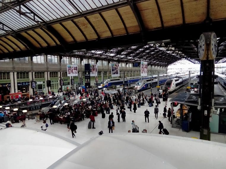 Vue plongeante du hall 1 de Paris-Gare-de-Lyon, foule de voyageurs et trains à quai sous la verrière.