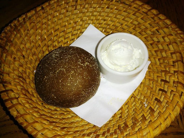 Tranches de pain de blé au miel recouvertes de fromage frais, alignées sur une assiette, prêtes pour un encas sucré-salé.