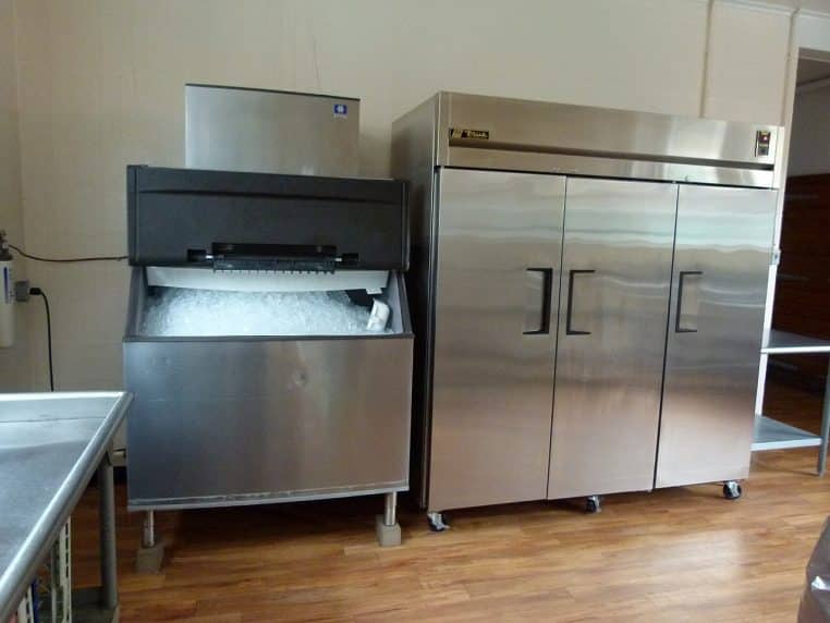 Machine à glaçons posée dans un espace collectif, prête à distribuer des glaçons pour rafraîchir les boissons des utilisateurs