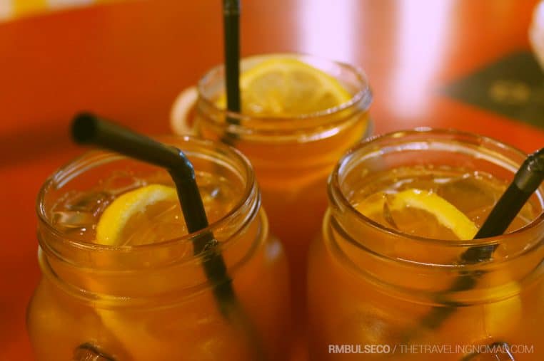 Trois verres mason jar remplis de boisson glacée au citron avec pailles noires, posés sur une table dans une ambiance chaleureuse