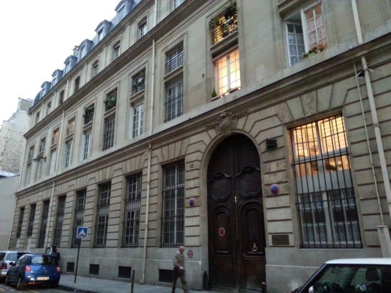 Façade du Crédit Municipal de Paris, 15 rue du Regard, vue de la rue avec le grand portail et les fenêtres illuminées.