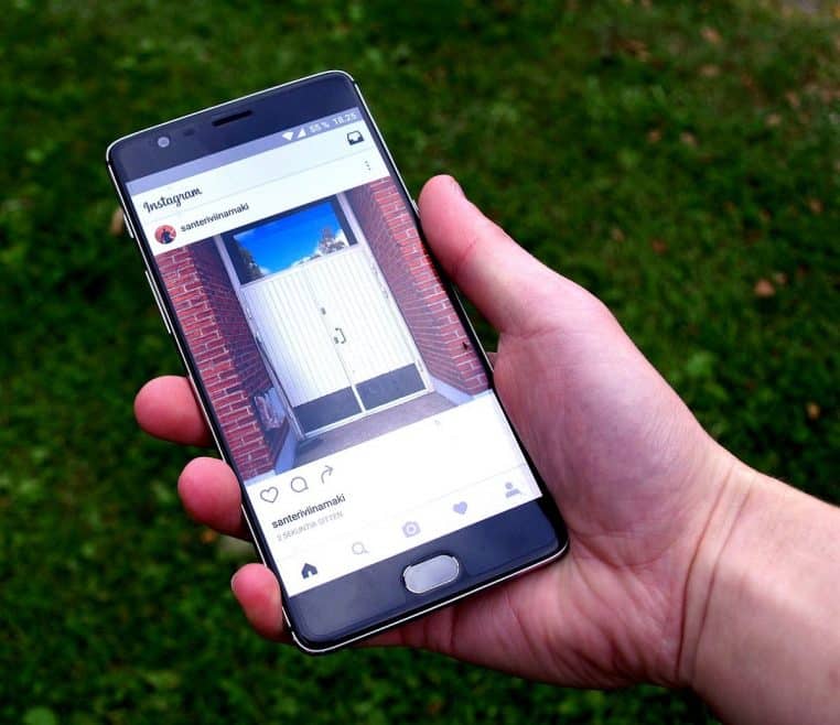 Écran de smartphone affichant l’application Instagram tenue en main, icônes visibles et mise au point nette