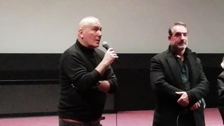 Jean Dujardin en 2022, expression dubitative en plan horizontal, prise de vue rapprochée et fond neutre.