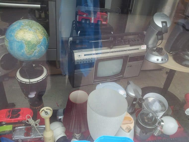 Vitrine de magasin de seconde main remplie d’objets hétéroclites, parfaite illustration d’une chasse au détail.