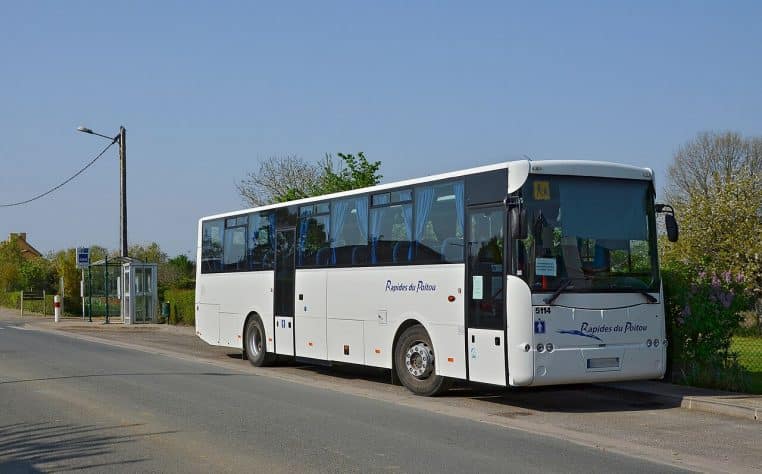 Bus scolaire jaune garé près d’un abribus le long d’une route de campagne en France, photographié en journée.