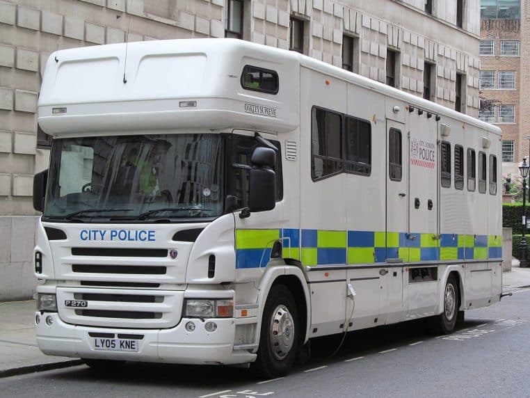 Grand camion remorque « City Police » destiné au transport de chevaux, garé dans une rue étroite en ville