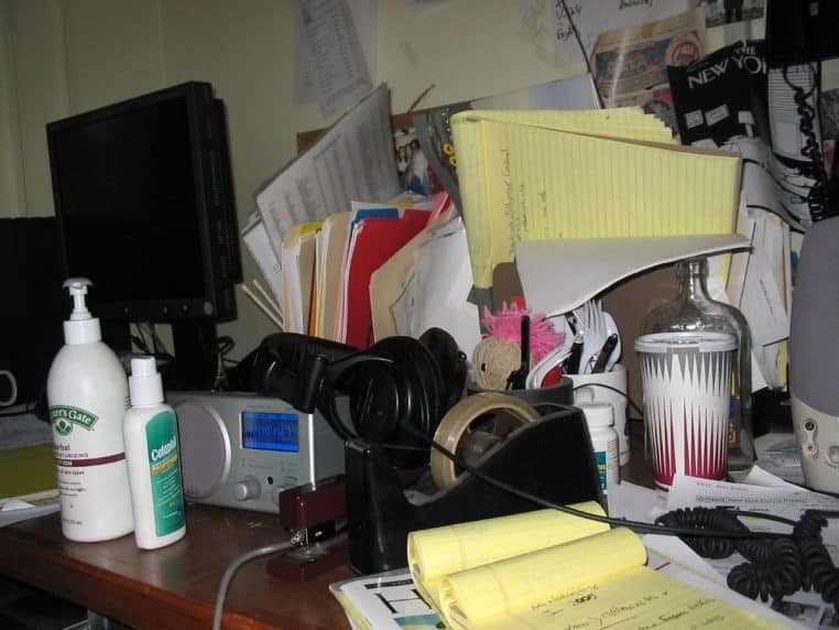 Bureau très encombré avec livres, papiers et objets empilés, symbole de surcharge mentale et de tâches en attente