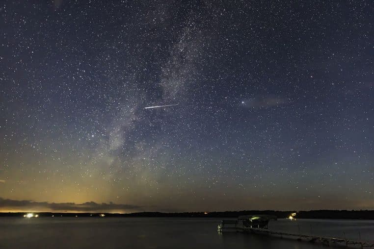 Voie lactée au-dessus d’un lac du Minnesota avec une Perséide lumineuse filant vers l’horizon, nuit d’été.