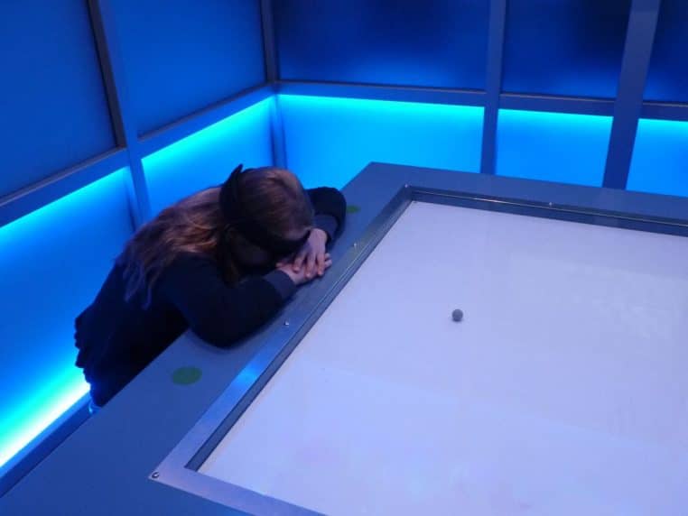 Des enfants assis face à face portent des bandeaux sensoriels pour faire avancer une balle sur une piste grâce à leur activité cérébrale.