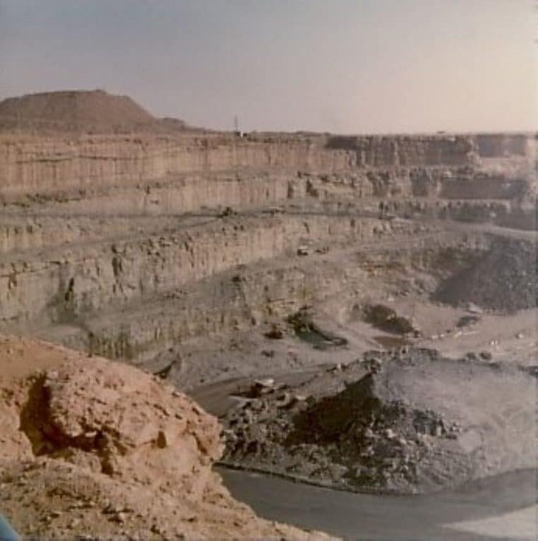 Large mine à ciel ouvert à Arlit au Niger, avec terrasses successives creusées dans la roche et engins d’extraction visibles au fond de la fosse