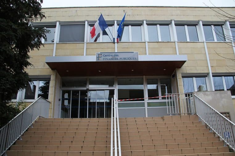Vue sur un centre des finances publiques d’une ville moyenne française, avec panneaux officiels indiquant la nature du service.