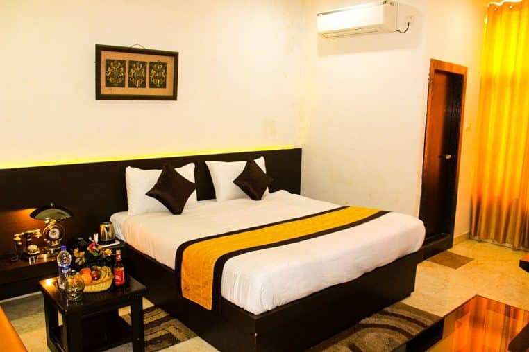 Chambre moderne avec grand lit, draps clairs et lumière douce, donnant une impression de confort et de propreté.