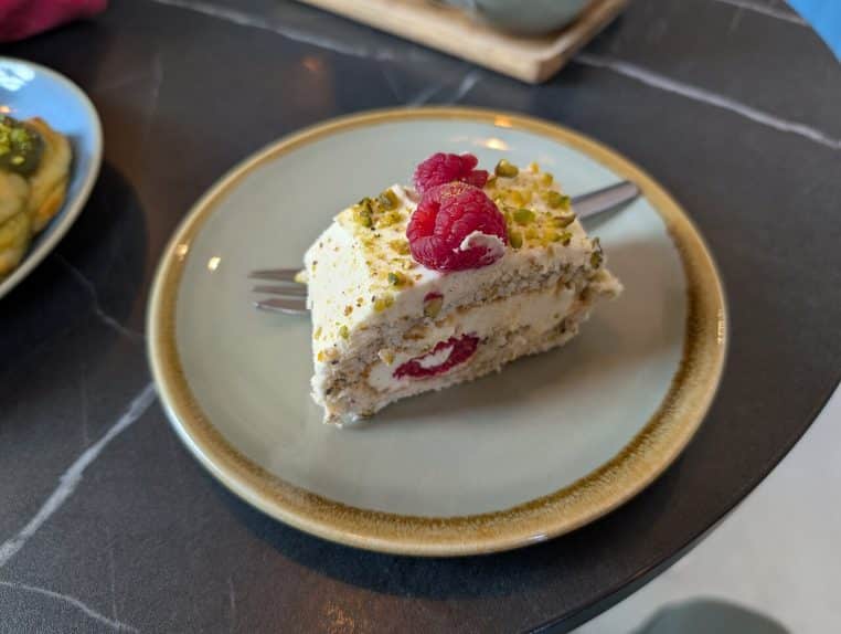 Roulé pistache et framboise présenté en tranches, avec crème colorée, évoquant une bûche de Noël garnie et prête à servir au réveillon.