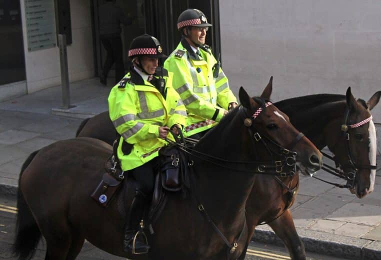 Deux policiers en veste haute visibilité montent des chevaux bruns en ville, photo prise en plongée sur la chaussée