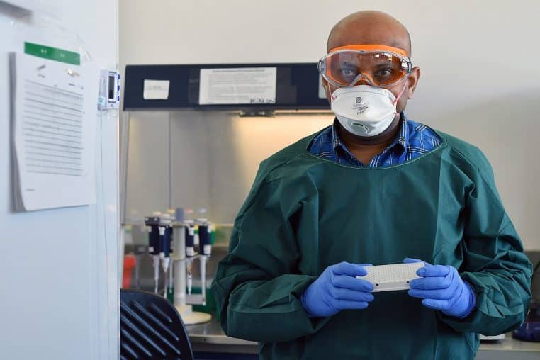 Technicien en laboratoire préparant un test, gants et pipette, pour illustrer des prélèvements et des analyses virologiques.
