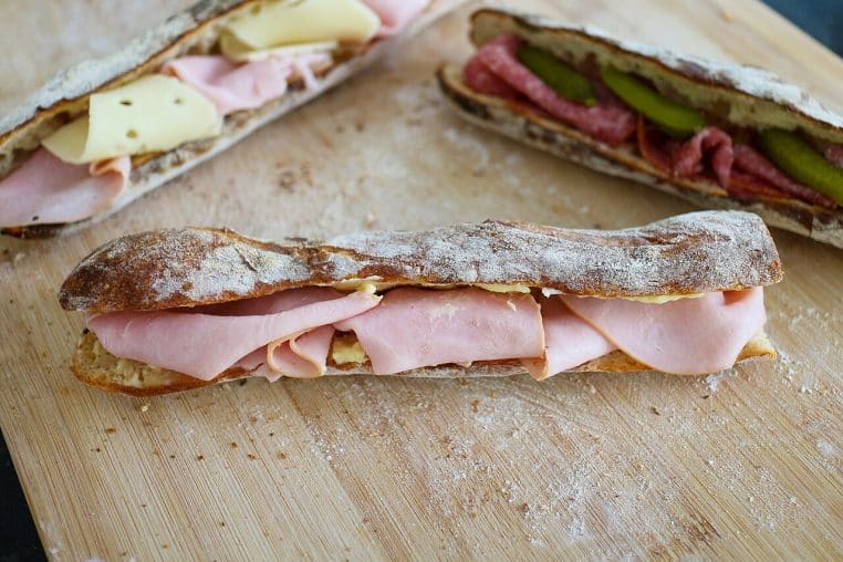 Sandwich jambon-beurre sur planche, charcuterie et pain, encas typique avant un départ en train.