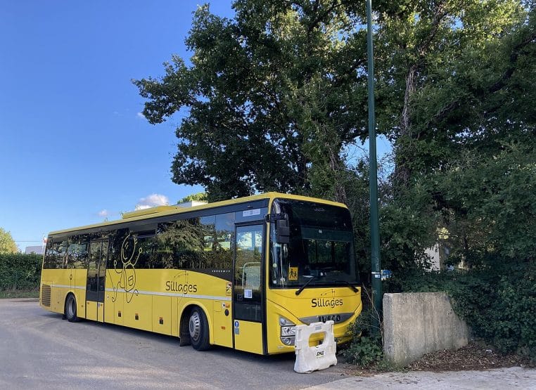 Autocar scolaire jaune du réseau Sillages arrêté près d’un trottoir dans un village du sud de la France.
