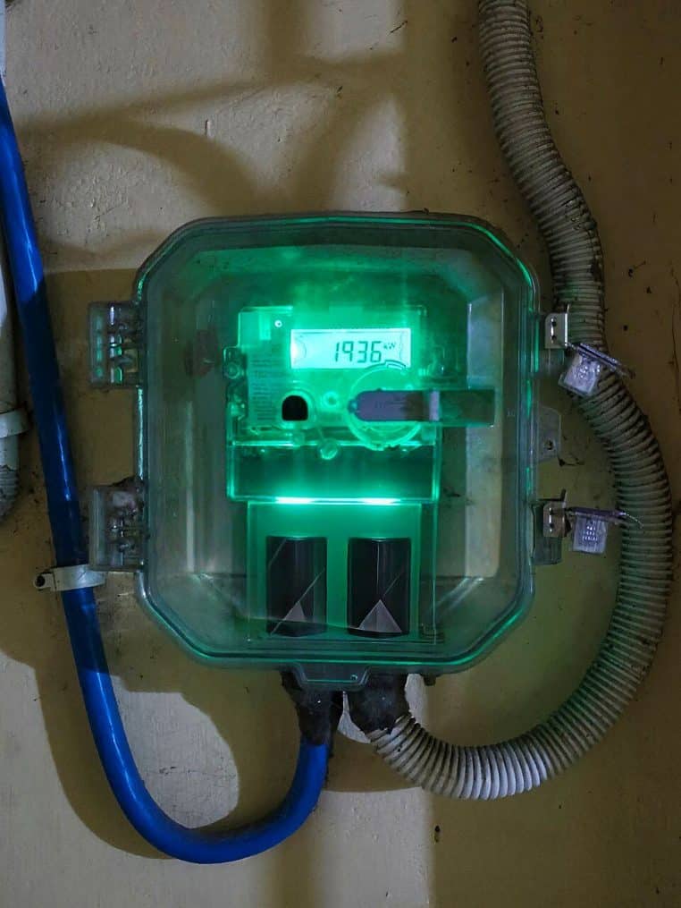 Compteur électrique numérique à affichage lumineux vert, fixé sur un mur intérieur, montrant clairement les chiffres de consommation d’énergie.