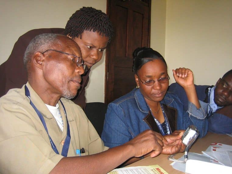 Équipe médicale réunie autour d’un appareil de communication, consultant des informations dans un cadre de télémédecine.
