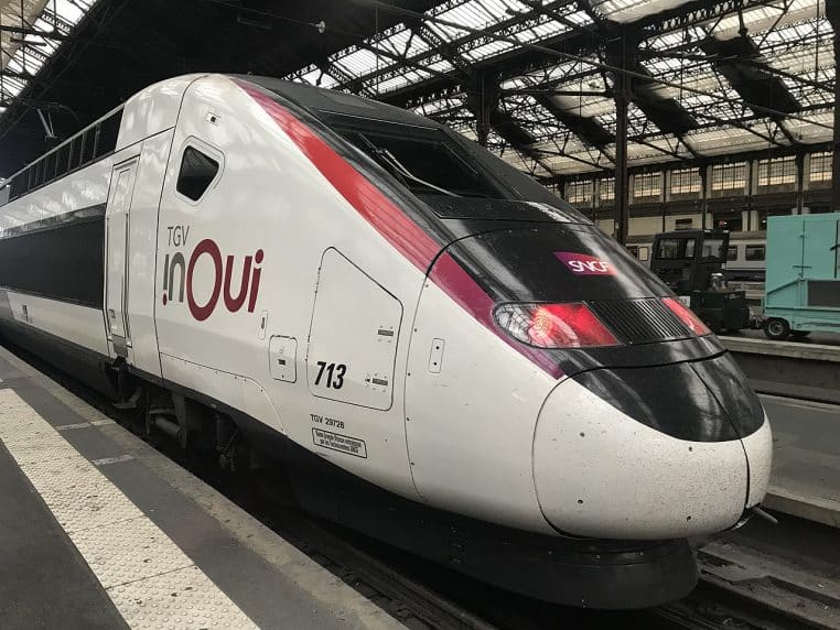 Un TGV InOui à quai à Paris-Gare-de-Lyon, voyageurs sur le quai et rames en arrière-plan, en journée.