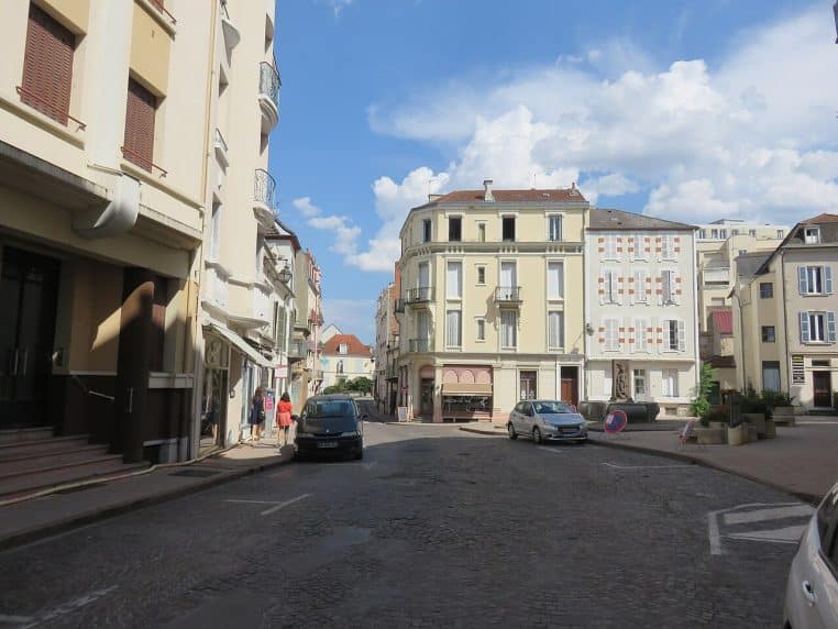 Vue de la place d’Allier à Vichy, rue pavée du centre-ville et bâtiments clairs sous un ciel bleu d’été.