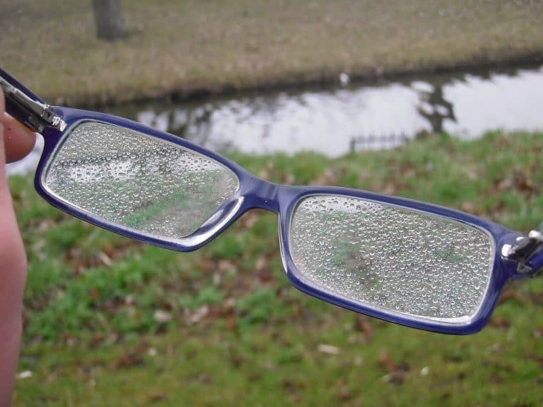 Gros plan de verres de lunettes humides avec gouttelettes, idéal pour illustrer un nettoyage doux au lavabo.