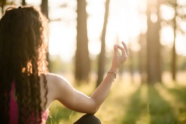 Main d’une femme en mudra de méditation, assise en plein air, pour évoquer l’apaisement émotionnel.
