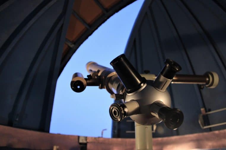 Intérieur d’un observatoire avec instrument d’astronomie pointé vers le ciel, ambiance de nuit.