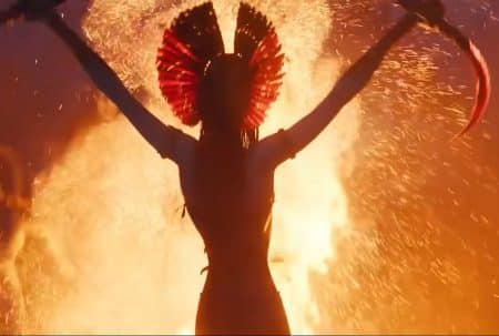 Silhouette d’une Na’vi brandissant des armes devant un brasier, scène rituelle et guerrière dans Avatar 3, ambiance feu et cendres.
