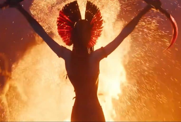 Silhouette d’une Na’vi brandissant des armes devant un brasier, scène rituelle et guerrière dans Avatar 3, ambiance feu et cendres.