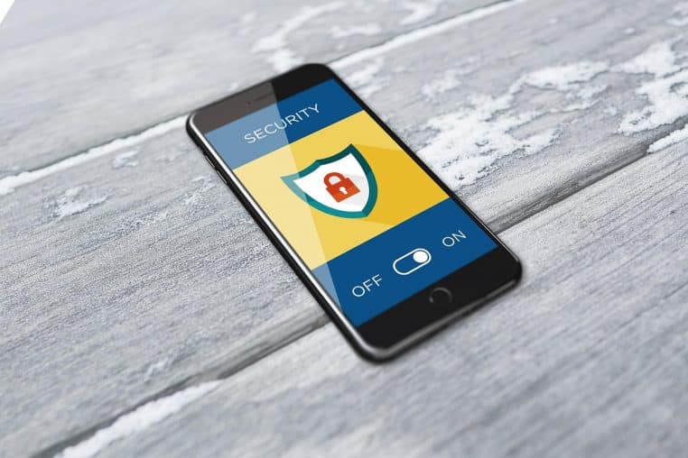 Gros plan sur un smartphone tenu en main devant un fond sombre, illustrant la cybersécurité et la protection des données mobiles