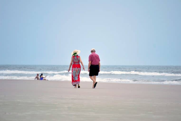 Couple de personnes âgées assis côte à côte en extérieur, souriants et détendus, illustrant le bien-être retrouvé à la retraite.