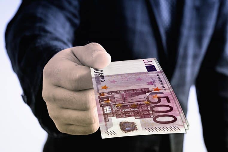 Main tendue offrant des billets en euros en guise de cadeau d’argent, illustrant un don entre particuliers ou familial au quotidien