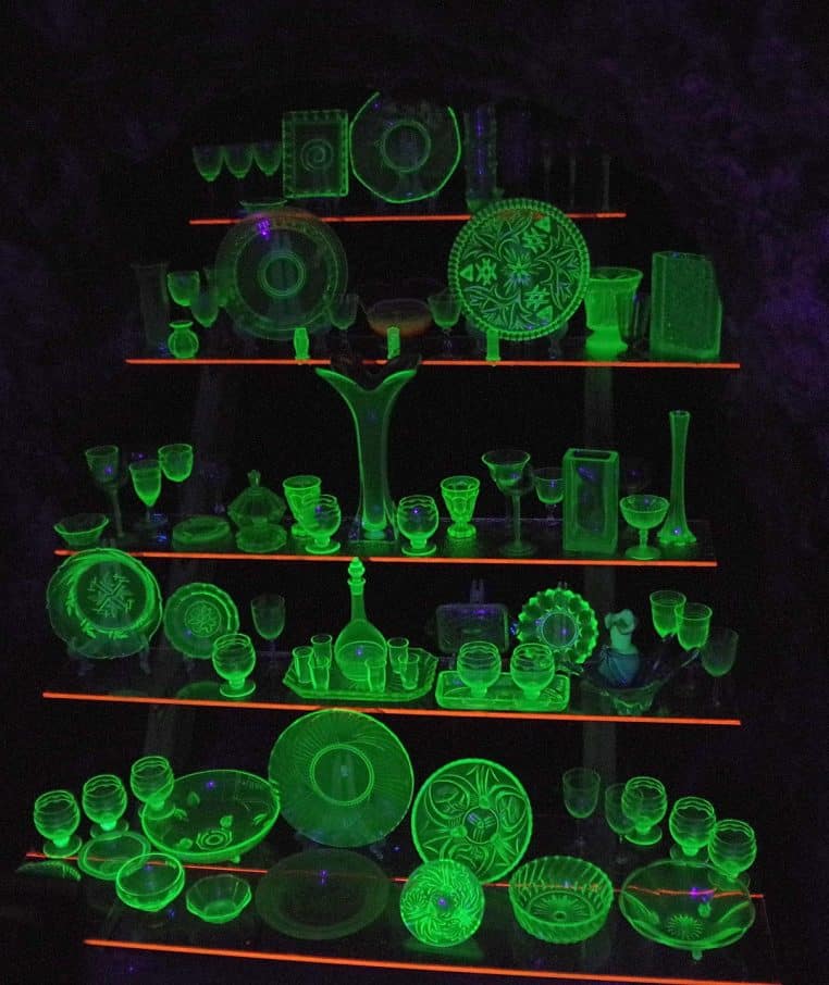 Petits flacons de verre alignés, éclairés en vert fluorescent dans l’obscurité, évoquant symboliquement la radioactivité et les substances nucléaires