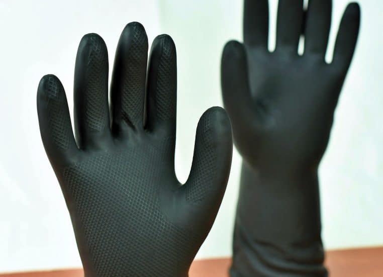 Paire de gants de ménage noirs en gros plan, symbole des précautions à prendre pour manipuler les produits d’entretien des WC.